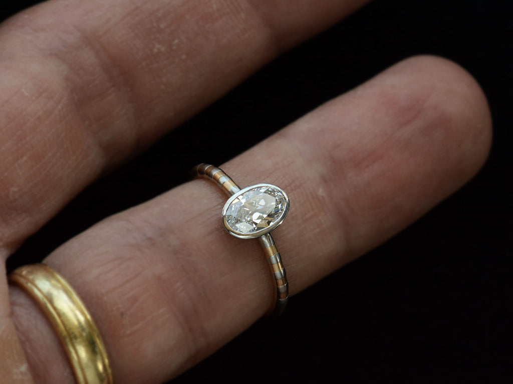 EB 0.69ct Oval Diamond Ring with Platinum Bezel and Striped Gold and Platinum Band (shown on finger for scale)