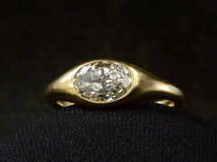 thumbnail of Right front angled view of flush set oval diamond ring in yellow gold, shown on dark background.
