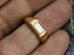 thumbnail of Face on view of EB Modern engagement ring with elongated emerald cut diamond flush set in a rounded 22k yellow gold mounting, on finger.