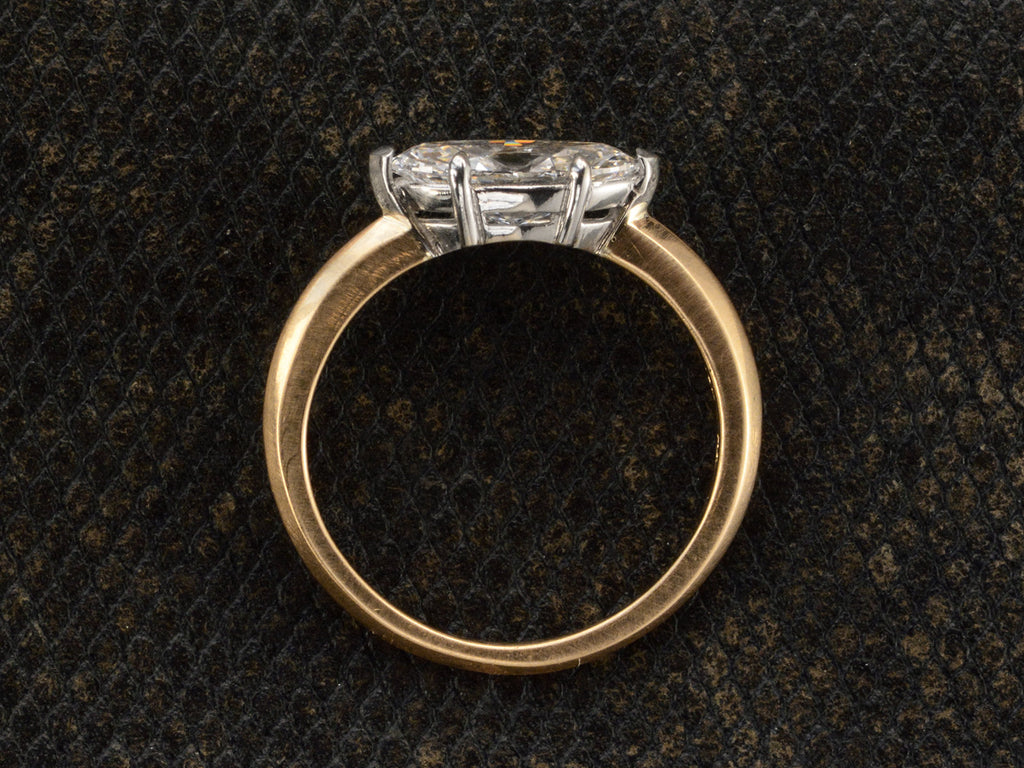 Side profile view of EB Modern engagement ring solitaire with marquise diamond set in platinum prongs with an 18K yellow gold knife edge shank, shown on dark textured background.