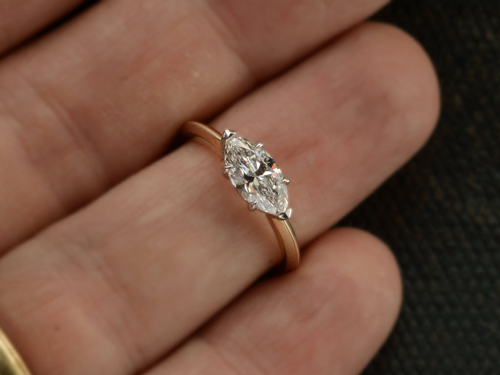 Front view of EB Modern engagement ring solitaire with marquise diamond set in platinum prongs with an 18K yellow gold knife edge shank, shown on finger