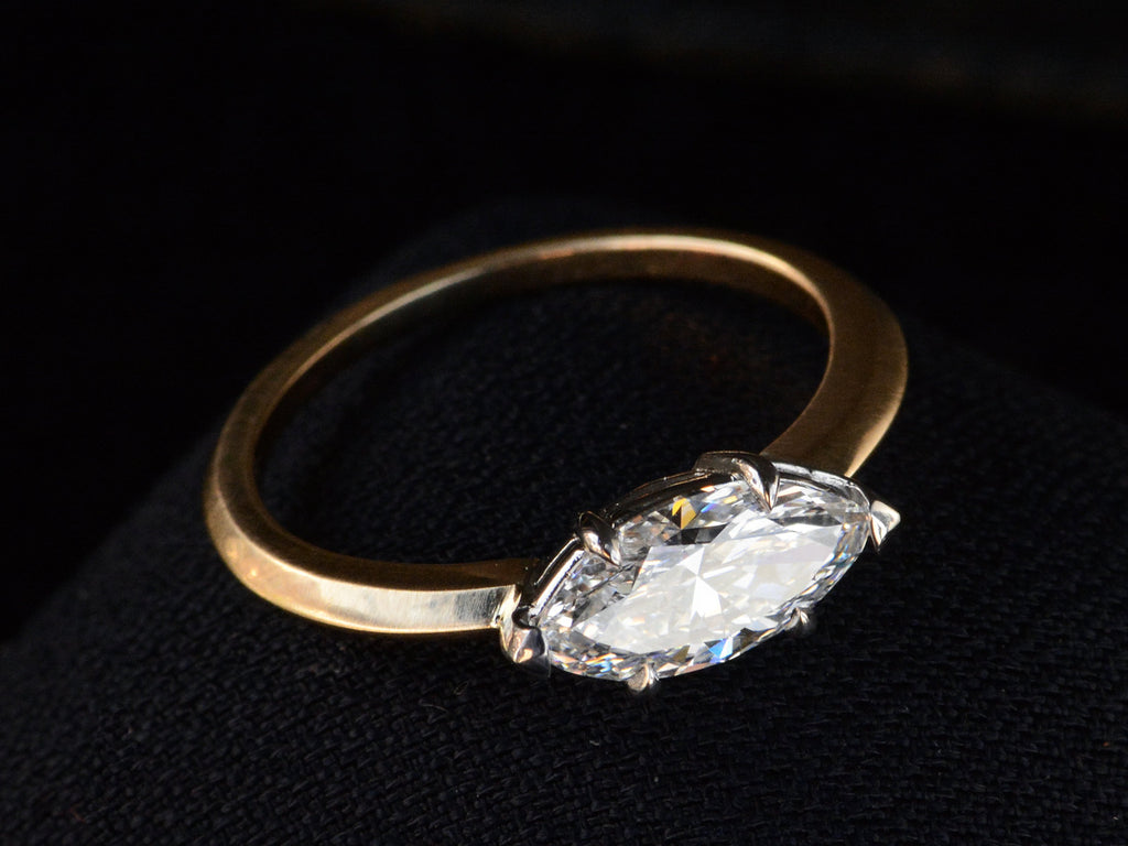 Detailed angled view of EB Modern engagement ring solitaire with marquise diamond set in platinum prongs with an 18K yellow gold knife edge shank, shown on dark background.