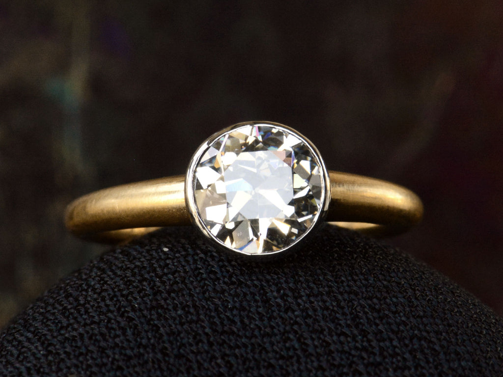 Front detail of EB Modern engagement ring with 1.42ct round diamond set in platinum bezel with round 18K yellow gold shank. Shown on dark background. 
