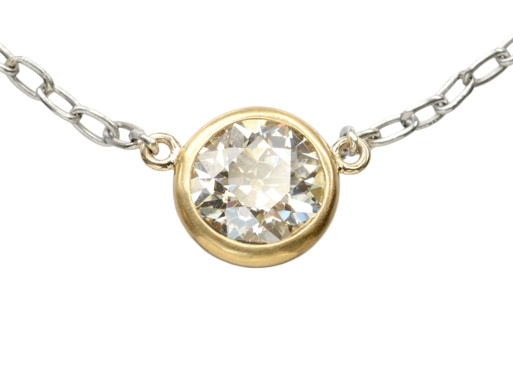 Detail of EB Modern necklace with round old cut diamond set in 22K yellow gold bezel on platinum chain. Shown on white background.
