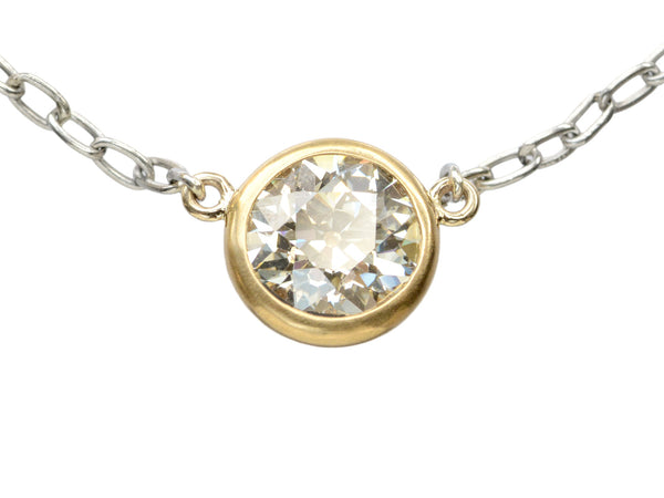 Detail of EB Modern necklace with round old cut diamond set in 22K yellow gold bezel on platinum chain. Shown on white background.