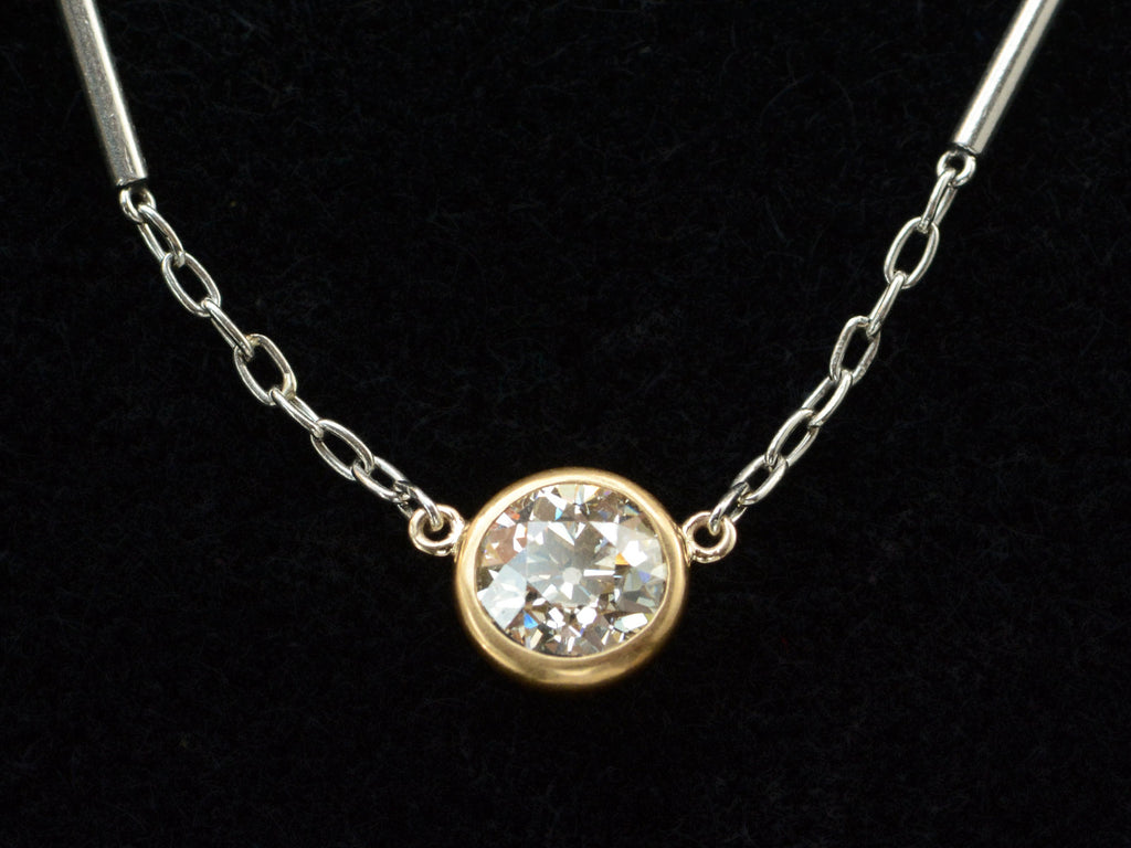 Detail of EB Modern necklace with round old cut diamond set in 22K yellow gold bezel on platinum chain. Shown on black background.