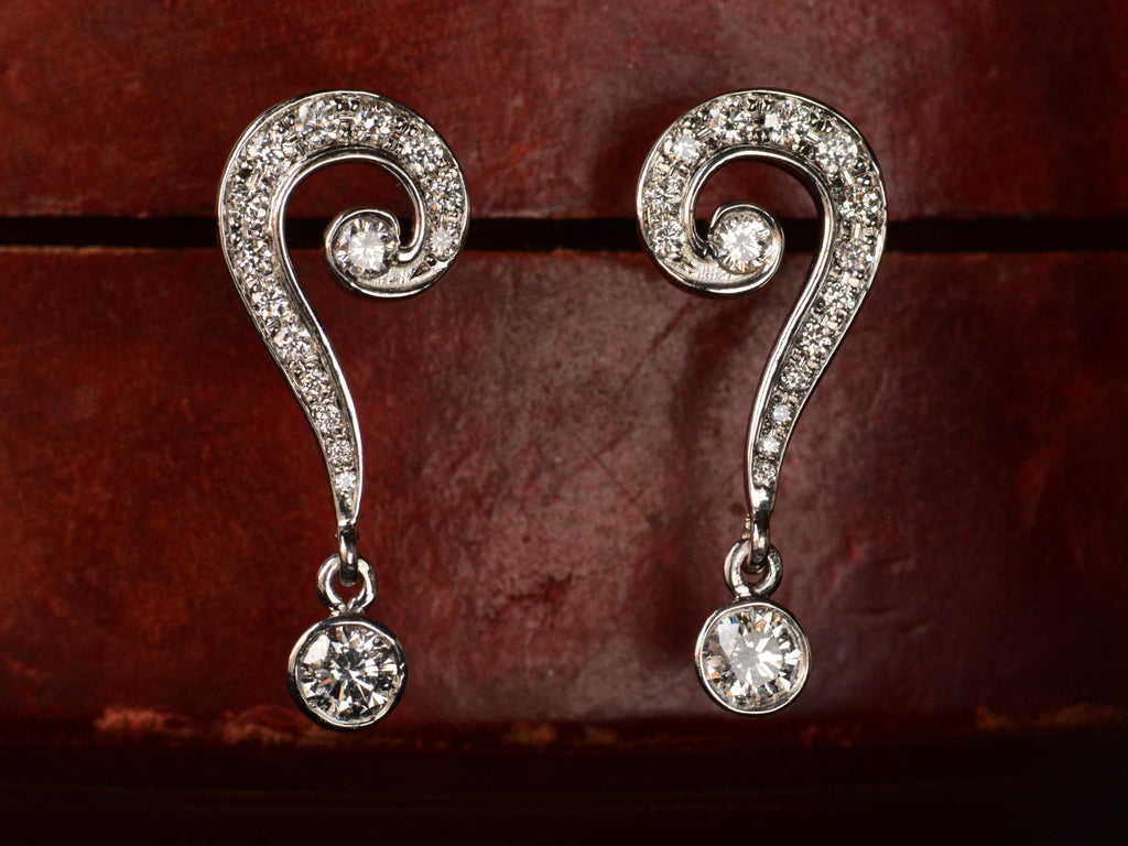 Front view of EB Question Mark Stud Earrings with brilliant cut diamonds set in platinum, shown on dark red background.