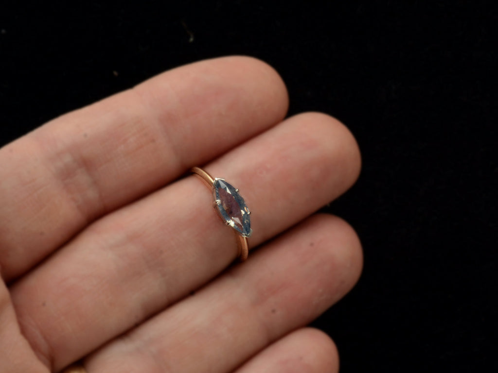 EB Modern ring with marquise-shaped light blue sapphire set in a simple platinum topped yellow gold mounting, shown on finger.