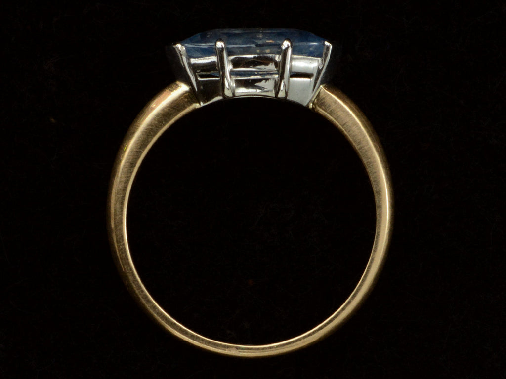 Side profile of EB Modern ring with marquise-shaped light blue sapphire set in a simple platinum topped yellow gold mounting, shown on black background.