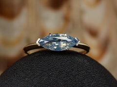 thumbnail of Front profile of EB Modern ring with marquise-shaped light blue sapphire set in a simple platinum topped yellow gold mounting, shown on black domed surface.