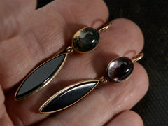 thumbnail of A pair of earrings with mismatched tops of moss agate and pink foiled rock crystal and navette shaped onyx drops, shown on hand
