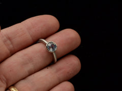thumbnail of Front view of a round opalescent light blue sapphire in a platinum bezel with a rounded matte platinum shank, shown finger.