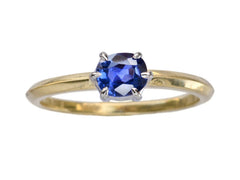 thumbnail of A cushion shaped blue sapphire ring set in platinum prongs over an 18K yellow gold knife edge shank, shown on white background.