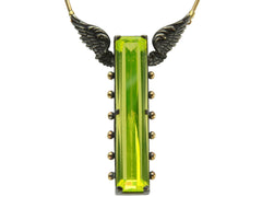 thumbnail of Detail of a pendant with a long florescent lime green uranium glass stone set in blackened silver with gold beads and wings on the mounting (on white background)