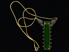thumbnail of Reverse side of pendant with a long florescent lime green uranium glass stone set in blackened silver with gold beads and wings on the mounting and yellow gold snake chain (on dark background)