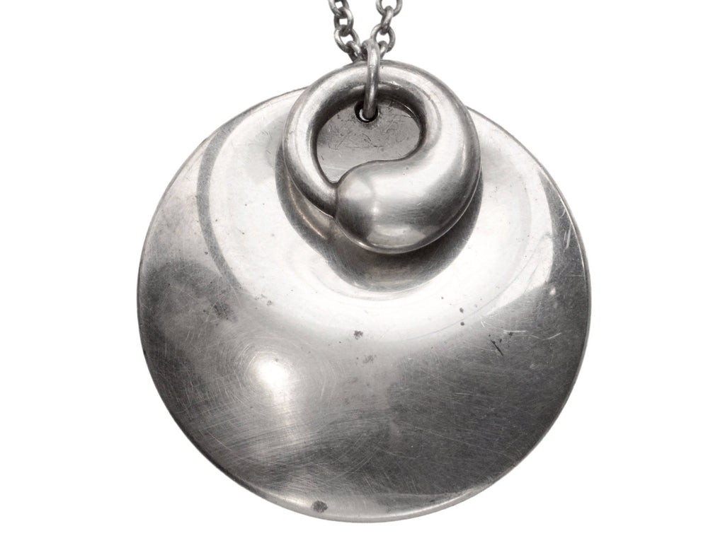 Pair of overlapping organic and minimal silver Elsa Peretti pendants, on white background. 
