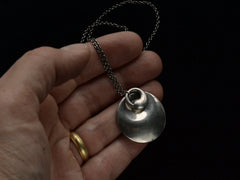 thumbnail of Pair of organic and minimal silver Elsa Peretti overlapping pendants hung on chain, held in hand.