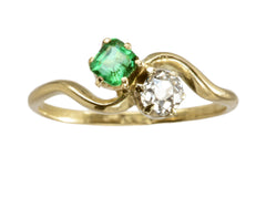 thumbnail of An antique Art Nouveau yellow gold wave-form ring with an emerald set opposite an old mine cut white diamond, shown on white background.