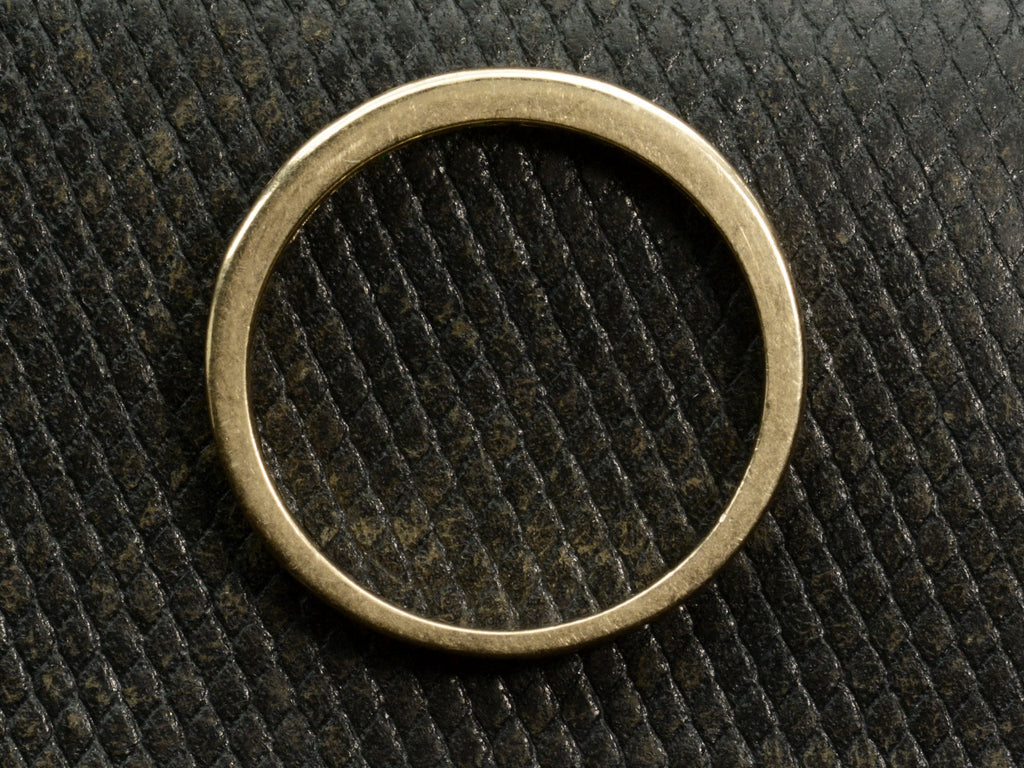 Side profile of gold ring on dark textured background.
