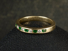 thumbnail of Angled view of a vintage gold ring with alternating emeralds and diamonds on a dark background