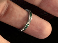 thumbnail of Vintage platinum eternity ring with alternating emeralds and diamonds on a finger.