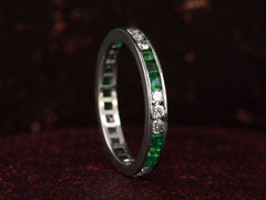 thumbnail of Vintage platinum eternity ring with alternating emeralds and diamonds on a dark background