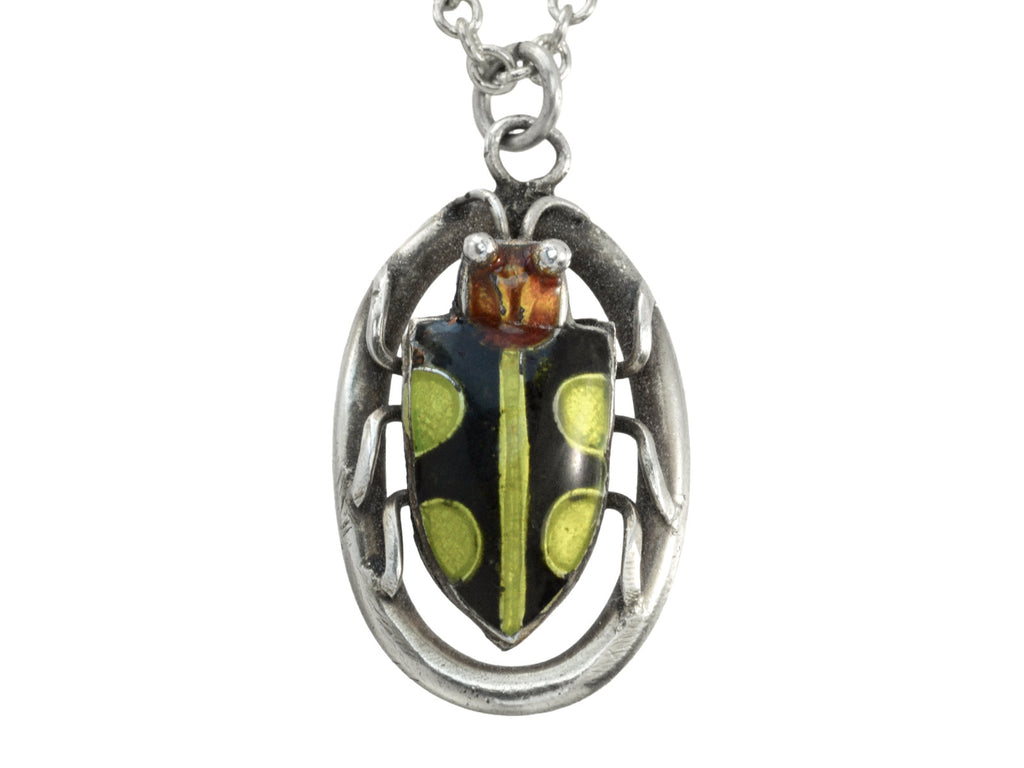Detail of c1920 Deco silver pendant with an red-headed, black and green enamel beetle set on an oval frame, shown on white background