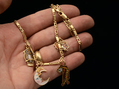 thumbnail of c1970 Enamel Charms Necklace (an owl, a moon, a tiger and a goldfish) in yellow gold. On a hand for scale.