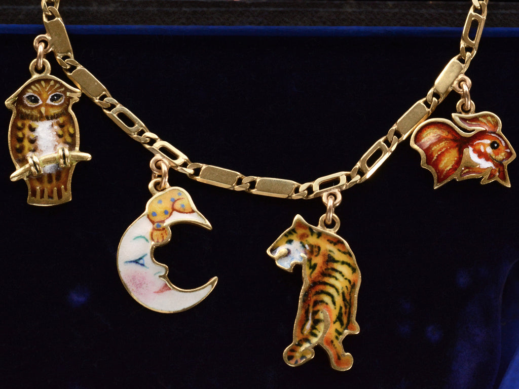 Detail view of c1970 Enamel Charms Necklace (an owl, a moon, a tiger and a goldfish) in yellow gold. On a dark blue background.