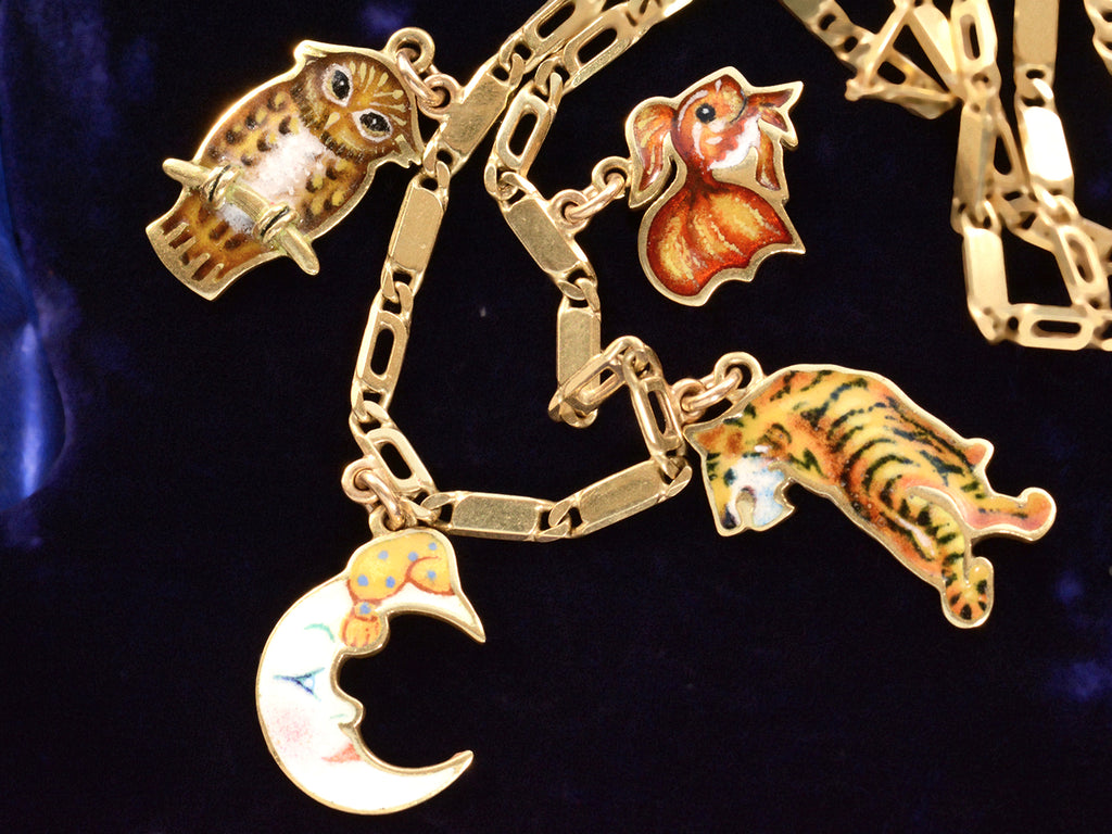 Detail view c1970 Enamel Charms Necklace (an owl, a moon, a tiger and a goldfish) in yellow gold. On a dark blue background.