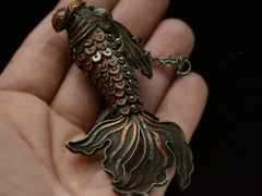 thumbnail of A vintage c1950 Chinese articulated fish pendant with orange enamel and filigree, shown on hand