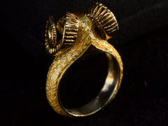thumbnail of Reverse back side view of a c1960 vintage ram's head ring in yellow gold with green emerald eyes and yellow and orange enamel details. Shown on dark background.