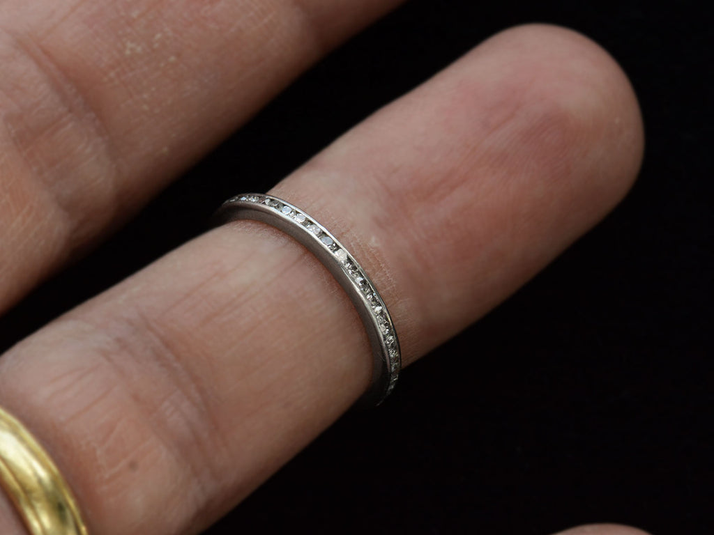 A thin vintage diamond eternity band in platinum, shown on finger