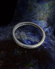 thumbnail of Angled view of a thin vintage diamond eternity band in platinum, shown on dark background