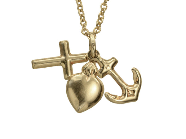 Detail of Italian yellow gold charm necklace with a cross, a heart and an anchor hanging on cable chain, shown on white background.