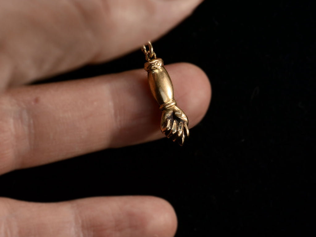 Vintage gold hand-shaped figa pendant on a chain held in hand