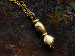 thumbnail of Reverse side of vintage gold hand-shaped figa pendant on a chain against a dark background