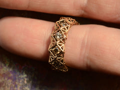 thumbnail of Front view of rosy-yellow gold eternity band with geometric filigree and brown diamonds. Shown on finger for scale.