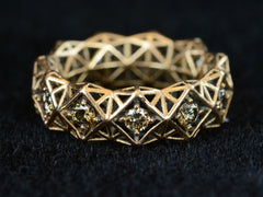 thumbnail of Front view of rosy-yellow gold eternity band with geometric filigree and brown diamonds. Shown on dark background.