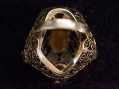 thumbnail of Reverse view of inside pentagonal Arts & Crafts movement ring with six fire opal cabochons set in a filigreed mounting, shown on dark background.