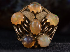 thumbnail of Front view of pentagonal Arts & Crafts movement ring with six fire opal cabochons set in a filigreed mounting, shown on dark background.