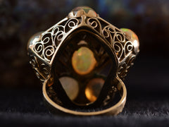 thumbnail of Reverse detail view of pentagonal Arts & Crafts movement ring with six fire opal cabochons set in a filigreed mounting, shown on dark background.