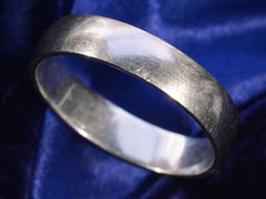 thumbnail of An angled view of a vintage c1980 flat men's wedding band in platinum, shown on a dark blue background.