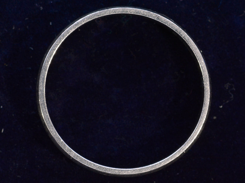 The side profile of a vintage c1980 flat men's wedding band in platinum, shown on dark background