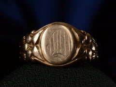 thumbnail of Front view of antique rose gold Art Nouveau signet ring with lily designs, shown on dark background. 