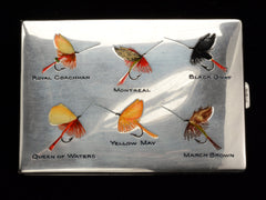 thumbnail of Silver cigarette case with fly fishing lures labeled 'Royal Coachman', 'Montreal', 'Black Gnat', 'Queen of Waters', 'Yellow May', and 'March Brown' on a black background.
