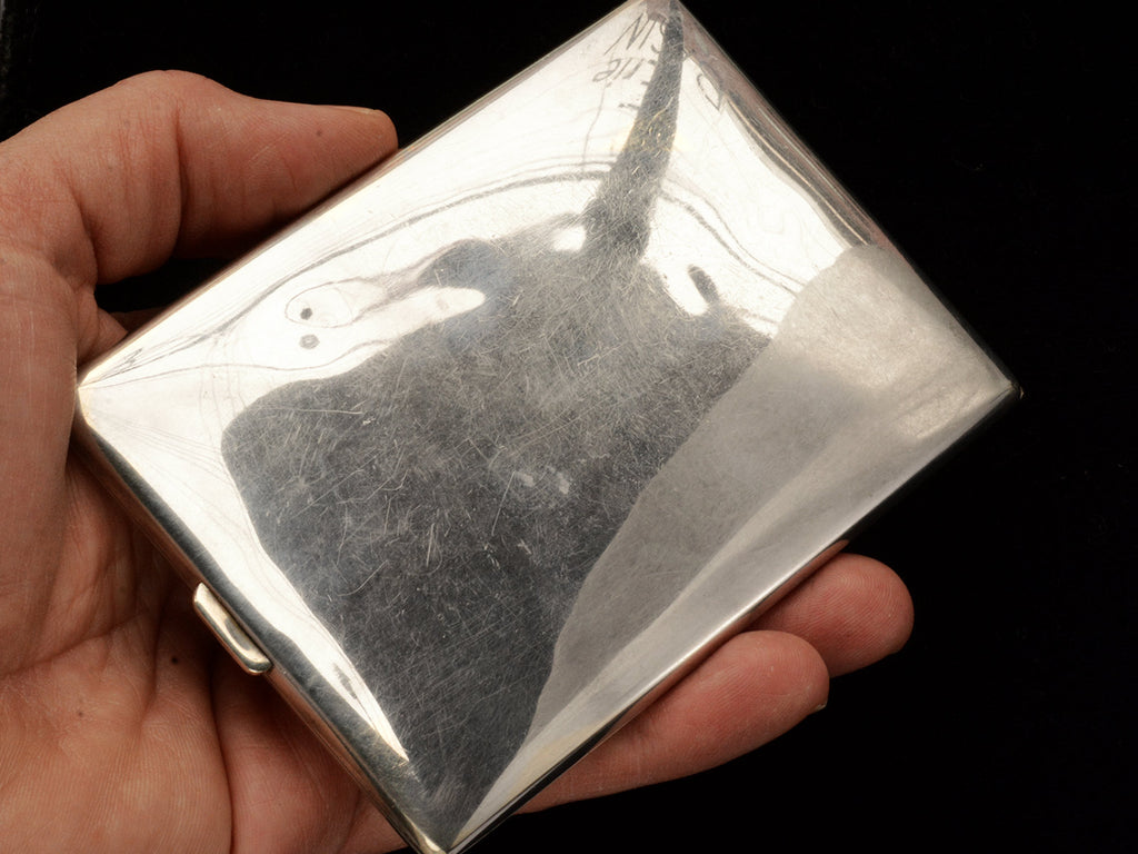 Reverse side of sterling cigarette case held in hand.