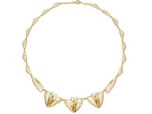 An antique French gold filigree necklace featuring three large butterfly motifs at the front, suspended from a delicate linked chain with small leaf-like elements, shown on a plain white background.