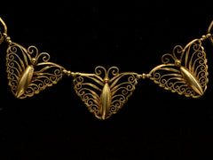 thumbnail of Detail of an antique French gold filigree necklace featuring three large butterfly motifs at the front, shown on black background.