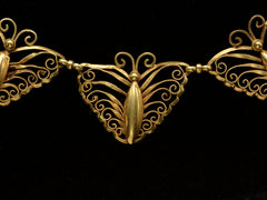thumbnail of Closer up detail of an antique French gold filigree necklace featuring three large butterfly motifs at the front, shown on black background.